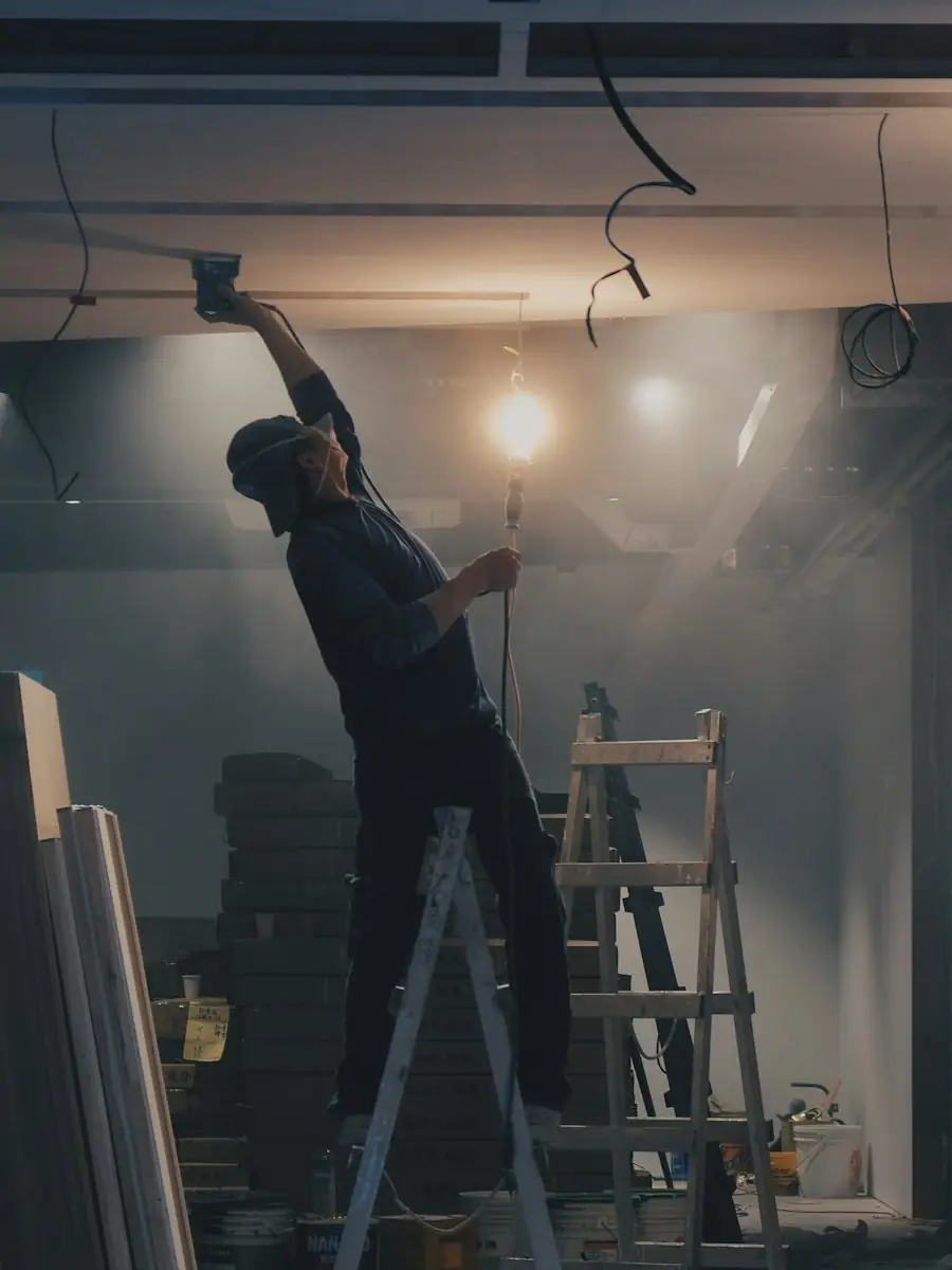 Worker removing ceiling fixtures from a ladder